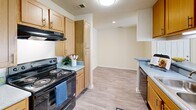 Located at 100 Willow Oak Dr in Columbia, SC, this single-floor, one-bedroom, one-bathroom residence offers a thoughtfully organized layout designed for comfortable everyday living. The kitchen is a functional galley-style space featuring warm wood cabinetry, light-toned countertops, black appliances including an electric range and dishwasher, and durable hardwood-style flooring. Ample upper and lower cabinet storage provides practical organization throughout. The kitchen flows seamlessly into the main living area, which continues the light hardwood-style flooring and is bathed in neutral tones. The spacious bedroom is finished with plush wall-to-wall carpeting and features a sliding glass door that opens to a private balcony with wooded views, filling the room with natural light. A closet offers dedicated storage within the bedroom. The bathroom is clean and efficiently designed, featuring a wood-toned vanity with a single sink, gray countertop, mirrored medicine cabinet, and hardwood-style flooring. A hallway connects the main areas of the unit, enhancing the flow between spaces. Textured ceilings are consistent throughout, and the overall neutral palette creates a bright, welcoming ambiance throughout the entire residence.