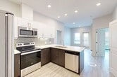Located at 10506 121 Avenue NW in Edmonton, Alberta, this thoughtfully designed two-bedroom, two-bathroom unit offers a smart and efficient layout across a single floor. Light-toned hardwood-style flooring runs throughout, creating a clean and cohesive aesthetic that complements the neutral grey and white colour palette.

The open-concept kitchen is a standout feature, equipped with stainless steel appliances including a full-size refrigerator, electric range, and over-the-range microwave. Two-tone cabinetry pairs dark wood lower cabinets with crisp white upper cabinets, accented by a grey subway tile backsplash and a white quartz peninsula countertop with an undermount sink — ideal for both cooking and casual dining.

The primary bedroom is generously proportioned and features large windows that invite an abundance of natural light along with views of the surrounding neighbourhood. Both bedrooms include closet storage, and the second bedroom also benefits from large windows with city views.

The two bathrooms are finished with tile flooring, white vanities with quartz countertops, and full tub-shower combinations. A dedicated in-suite laundry area adds everyday convenience. Recessed lighting throughout the living areas enhances the bright, modern ambiance of this well-appointed urban residence.