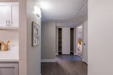 This thoughtfully designed single-floor residence offers a comfortable and cohesive layout with modern finishes across every room. The living area serves as the heart of the home, featuring wood-look flooring, a textured ceiling, and a sliding glass door flanked by vertical blinds that invite natural light into the space. A stylish round coffee table, contemporary lighting fixtures, and curated wall art contribute to the room's warm, inviting ambiance. Adjacent to the living area, the dining space accommodates a round table with seating for several guests, accented by a modern ceiling fan and a window that provides additional natural light. The galley-style kitchen is efficiently designed with white shaker cabinetry, white countertops, and stainless steel appliances, including a refrigerator and electric range. A hallway with wood-look flooring connects the bedrooms and includes a built-in open closet for additional storage. Both bedrooms feature carpeted floors, windows with blinds, and closet space. The primary bedroom offers a tufted upholstered headboard and bold wall art, while the secondary bedroom includes a reach-in closet. Two bathrooms serve the residence — one with a tub-shower combo and a vanity with gray cabinetry, and a second half-style bath with a white countertop vanity and framed mirror. Throughout, the neutral color palette and consistent design language create a clean, modern atmosphere.