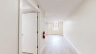 Located at 501 Washington St in Reading, PA, this efficiently designed single-floor unit offers a clean, modern aesthetic with thoughtful finishes throughout. Light wood-tone flooring runs continuously across the entire space, creating a cohesive and bright atmosphere.

The open-concept kitchen and living area forms the heart of the unit. The kitchen is well-appointed with shaker-style cabinetry in a soft gray-white finish, black hardware accents, white countertops, and a full suite of stainless steel appliances including a range, dishwasher, and refrigerator. A sleek black gooseneck faucet and under-cabinet range hood complete the functional setup. A window in the kitchen area provides a view of the surrounding brick exterior architecture, drawing in natural light.

The living area is open and versatile, illuminated by recessed ceiling lights and a window that continues to bring in natural light. The neutral, warm beige walls offer a blank canvas throughout the space.

A hallway connects the main living area to the bathroom and entry, featuring recessed lighting and a bold blue entry door that adds a distinct design touch. The bathroom is spacious and accessibility-conscious, equipped with a tub-shower combination featuring a sliding black-framed enclosure, grab bars, and light flooring consistent with the rest of the unit. The overall space is clean, modern, and move-in ready.