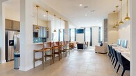Located at 6160 Hall Rd in Galloway, Ohio, this well-appointed single-story community space offers a thoughtfully designed layout across a generously sized floor plan. The welcoming entrance foyer features soaring ceilings, light tile flooring, and structural columns that frame the open-concept interior, setting an inviting tone from the moment you arrive.

The combined kitchen and living area serves as the heart of the space. The kitchen is outfitted with warm wood cabinetry, a striking blue tile backsplash, stainless steel appliances, and a white quartz peninsula bar topped with leather-seated barstools and illuminated by a row of elegant brass pendant lights. The adjacent living area features a floor-to-ceiling whitewashed brick fireplace, large windows dressed in bold patterned drapery, and a wall-mounted television, creating a comfortable and visually dynamic gathering space.

The dedicated media room offers a more intimate retreat, complete with a large wall-mounted screen, plush neutral seating, warm leather accent chairs, and ample natural light from oversized windows with plaid curtains. A popcorn machine adds a fun, cinematic touch.

Throughout, the space maintains a cohesive aesthetic of neutral tones accented by blue textiles, brass fixtures, and tile flooring, resulting in an atmosphere that is both stylish and functional for community gatherings.