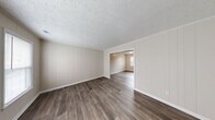 Located at 704 Windy Hill Dr in Fayetteville, NC, this two-story home offers a well-designed layout with a blend of practical finishes and modern updates throughout. The main living area welcomes you with rich, dark hardwood-style flooring and distinctive vertical shiplap-style wall paneling, lending a clean, contemporary character to the space. A staircase leads to the upper level, and a louvered-door closet provides convenient main-floor storage. The kitchen is a standout feature, showcasing crisp white shaker-style cabinetry, granite-look countertops, a classic white subway tile backsplash, and a stainless steel double-basin sink — a functional and attractive space for everyday use. The bedrooms are generously sized, finished with plush carpeting and ceiling fans for year-round comfort. One bedroom notably features dual closets, offering excellent storage capacity, along with a window that brings in natural light. The bathrooms are thoughtfully appointed, with one full bath featuring a tub-shower combination and wood-look flooring, and a half bath with a granite-topped vanity and a large mirror. Textured ceilings are consistent throughout the home, adding subtle architectural detail to every room.