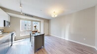 Located at 240 Chicago Ave in Minneapolis, MN, this efficiently designed studio offers a thoughtfully organized single-floor layout. The combined kitchen and living area serves as the heart of the space, featuring light wood-style flooring, neutral warm-gray walls, and generous natural light from a large window with urban views. The modern kitchen is well-appointed with stainless steel appliances including a full-size French door refrigerator, gas range, microwave, and dishwasher. Two-tone cabinetry — white upper cabinets paired with gray lower cabinets — is complemented by a classic subway tile backsplash and under-cabinet lighting. A freestanding kitchen island with built-in shelving and a dark countertop provides additional prep and dining space. Track lighting overhead enhances both function and ambiance. A bright hallway connects the living area to the bathroom and two closets, offering practical storage solutions. The bathroom features a sleek, floating vanity with dark wood-toned cabinetry, a white countertop, and a backlit mirror, creating a clean and contemporary feel. In-unit laundry adds everyday convenience. Throughout, the consistent wood-style flooring and soft neutral palette create a cohesive, modern aesthetic.