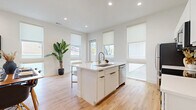 Located in Dallas's 75206 zip code, this single-floor residence delivers a thoughtfully designed modern living experience. Light hardwood floors run throughout, complementing the crisp white walls and recessed lighting that create a bright, airy atmosphere.

The open-concept kitchen is a standout feature, centered around a large island with a white quartz countertop, an undermount sink, and gold-toned faucet hardware. White flat-panel cabinetry lines the walls, paired with a full suite of stainless steel appliances including a refrigerator, range, microwave, and dishwasher. Multiple large windows with roller shades bathe the kitchen and adjoining living and dining areas in natural light. The seamless flow between these spaces makes the layout feel expansive and well-connected.

The living area offers generous space for seating and dining, with tall windows framing outdoor views and contributing to the home's open, welcoming ambiance.

The bedroom features a ceiling fan, built-in closets, and a window that allows natural light to filter in, providing a calm and restful retreat.

The bathroom is finished with a grey hexagonal tile floor, white floating vanity with gold hardware, a tub-shower combination, and matte black and gold accent fixtures — a refined blend of modern and contemporary design elements throughout.