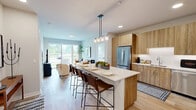 Located at 5424 Old Orchard Rd in Skokie, IL, this thoughtfully designed residence offers a modern aesthetic with clean lines and warm, contemporary finishes throughout. Light oak hardwood flooring flows seamlessly across the entire single-floor layout, lending a cohesive and airy feel to every room.

The kitchen is a standout feature, showcasing flat-panel wood cabinetry, white quartz countertops, stainless steel appliances, and a large island with seating for multiple guests — all illuminated by pendant lighting overhead. The adjacent living room is bright and welcoming, anchored by expansive sliding glass doors that frame outdoor views and flood the space with natural light.

The primary bedroom offers a comfortable and serene retreat, complete with a large window overlooking the greenery outside and direct access to a dedicated closet. Two full bathrooms serve the home: one features a tiled soaking tub and wood-toned vanity, while the other includes a glass-enclosed walk-in shower, mosaic tile flooring accents, and a matching vanity with a lighted mirror. A flexible office space and two closets add to the home's functional versatility. The overall ambiance is modern, light-filled, and well-organized, making efficient use of every square foot.