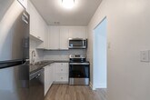 Located at 835 Sherbrooke St in Peterborough, Ontario, this well-appointed one-bedroom, one-bathroom unit offers a clean, modern aesthetic throughout its efficiently designed single-floor layout. Light-toned hardwood-style flooring runs continuously across the space, creating a cohesive and airy feel.

The combined living and dining area is bright and welcoming, featuring large windows with wide sills and baseboard heating beneath them, allowing natural light to pour in while offering views of the surrounding neighbourhood. The open layout provides a versatile space for both relaxing and dining.

The kitchen is thoughtfully updated, showcasing white shaker-style cabinetry with brushed nickel hardware, grey countertops, a classic white subway tile backsplash, and a full suite of stainless steel appliances including a range, over-the-range microwave, and refrigerator.

The bedroom is a comfortable, well-proportioned room with a large window, baseboard heating, and a sliding-door closet, providing practical storage. The clean white walls and light flooring give the room a calm, restful ambiance.

The bathroom is finished with crisp white subway tile surrounding a full soaker tub and shower combo, complemented by chrome fixtures for a timeless, polished look. Overall, the unit presents a fresh, updated interior ideal for comfortable everyday living.