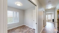 This two-floor home offers a clean, modern aesthetic with a neutral color palette and thoughtfully designed living spaces. The main living area is a standout, featuring rich wood-look flooring, a white-surround fireplace with a sleek black insert, and multiple windows fitted with blinds that fill the room with natural light. A door from the living area provides direct outdoor access, enhancing the open feel of the space.

The kitchen is well-equipped with stainless steel appliances, including a range, over-the-range microwave, and dishwasher, complemented by contemporary flat-front cabinetry in a warm wood-tone finish and light quartz-style countertops.

The bedrooms are carpeted for comfort and feature mirrored sliding closet doors that amplify the sense of space. Each bedroom benefits from natural light through blinds-equipped windows, and the rooms connect to a hallway with wood-look flooring. One bedroom includes a sliding barn-style door, adding a subtle design detail.

The bathroom is clean and functional, featuring a full tub-shower combination with brushed nickel fixtures, a vanity, and a mirror. Throughout the home, white panel doors, crisp baseboards, and a consistent neutral palette create a cohesive and move-in-ready environment across both floors.
