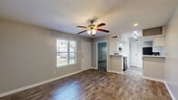 Located at 305 W Baker Rd in Baytown, TX, this single-story, one-bedroom, one-bathroom unit offers a practical and well-appointed layout across a compact but efficiently designed floor plan. The combined living and dining area serves as the heart of the home, featuring durable wood-look flooring, neutral gray walls, white baseboards, and a ceiling fan with integrated lighting. A front-facing window allows natural light to fill the space, creating a bright and welcoming atmosphere. The front entry opens directly into this area, which also connects seamlessly to the kitchen via a peninsula-style counter. The galley kitchen is outfitted with white cabinetry, a light-toned countertop, a stainless steel sink, and black appliances including a range and refrigerator. A pantry provides additional storage, and light-toned flooring completes the clean, functional look. The bedroom offers a comfortable footprint with wood-look flooring, neutral walls, a window with outdoor views, and a built-in closet with sliding mirrored doors for convenient storage. A full bathroom and a dedicated closet round out the unit. Throughout the space, consistent finishes and a neutral color palette contribute to a cohesive, move-in-ready feel.
