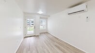 Located at 435 Gateway Dr in Pacifica, CA, this one-bedroom, one-bathroom unit offers a clean, modern layout across a single floor. Light wood-style flooring flows throughout the space, complementing the crisp white walls and creating a bright, cohesive aesthetic.

The living room is a comfortable, open area featuring a wall-mounted mini-split HVAC unit, recessed lighting, and a glass-panel door that opens directly to an outdoor area, allowing natural light to fill the room. A large window with blinds further enhances the airy feel.

The kitchen is well-appointed with white shaker-style cabinetry, white countertops, and a full suite of stainless steel appliances, including an electric range, over-the-range microwave, refrigerator, and dishwasher. The layout is efficient and functional, with ample cabinet storage extending to the ceiling.

The bedroom is a well-proportioned retreat featuring light wood-style flooring, white walls, and a sliding double-door closet. The clean, minimalist design makes the space feel open and versatile.

The bathroom is finished in all-white with a full tub-and-shower combination featuring built-in shelving, a white vanity with cabinet storage, and a gold-tone towel ring accent. The overall design throughout the unit is modern, clean, and move-in ready.
