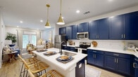 Located at 900 Corby Lane in Charleston, SC, this thoughtfully designed one-bedroom, one-bathroom residence makes excellent use of its single-floor layout. The kitchen is a standout, showcasing rich navy blue shaker cabinetry accented with gold hardware, a white subway tile backsplash, stainless steel appliances, and a peninsula island with seating — all illuminated by brass pendant lights. Light wood-style flooring flows throughout, unifying the open-concept living and kitchen areas. The living room is bright and welcoming, featuring recessed lighting, large windows with natural light, and access to an outdoor area framed by floor-length drapery. The bedroom offers a calm retreat with a ceiling fan, multiple windows, and a botanical-patterned accent wall that adds character. A dedicated walk-in closet provides generous shelving and storage. The bathroom continues the navy and gold design theme with a bold vanity, white countertops, a soaking tub, and a subway-tiled shower. Light wood flooring and crisp white walls maintain a cohesive, modern aesthetic throughout this well-appointed Charleston residence.
