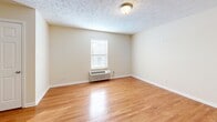 Located at 6301 W Kilgore Ave in Yorktown, Indiana, this single-floor, one-bedroom, one-bathroom unit offers a well-organized and functional layout. The combined kitchen and living area forms the heart of the home, with warm hardwood flooring flowing throughout the living spaces and neutral-toned walls creating a clean, bright atmosphere. The kitchen is well-equipped with stainless steel appliances — including a range, microwave, dishwasher, and refrigerator — complemented by warm wood cabinetry and granite-look countertops, all set atop classic tile flooring. The bedroom is a comfortable, dedicated retreat featuring hardwood floors, a window with natural light, and a wall-mounted HVAC unit. The full bathroom includes a wood vanity with a granite-style countertop, a large mirror, tile flooring, and clean white fixtures. The unit also includes a dedicated laundry space and three closets, providing ample storage throughout. Textured ceilings are consistent across all rooms, adding a familiar residential character. This thoughtfully arranged unit offers practical everyday living in a straightforward, move-in-ready package.