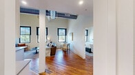 Located at 219 N Columbus St in Lancaster, Ohio, this 2-bedroom, 2-bathroom residence masterfully combines historic architectural character with modern design. The open-concept kitchen and living area serves as the heart of the home, where rich hardwood floors and soaring ceilings set an impressive tone. The kitchen features white shaker cabinetry, stainless steel appliances, a large island with pendant lighting and bar seating, and a convenient entry area with a distinctive teal door. The living room is bathed in natural light from oversized windows with city views, highlighted by exposed white-painted brick walls that add texture and charm. Both bedrooms offer generously proportioned layouts with the same dramatic ceiling heights, hardwood floors, and large windows. The primary bedroom includes dedicated closet space with built-in wire shelving. The two bathrooms are thoughtfully designed — one with a sliding glass-enclosed walk-in shower and subway tile, the other with a full tub/shower combination — both featuring hexagonal mosaic tile floors and matte black hardware accents. A hallway connects all spaces efficiently, and two closets provide ample storage throughout. This residence offers a compelling blend of urban character and updated comfort.