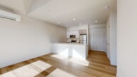 Located at 2101–2115 174th St NE in Marysville, WA, this 2-bedroom, 1-bathroom unit offers a thoughtfully designed open-concept layout finished with light hardwood flooring throughout. The living area is a standout, featuring soaring vaulted ceilings and a dramatic triangular window arrangement that floods the space with natural light while framing views of the surrounding neighborhood. A sliding glass door provides direct access to an outdoor balcony, further enhancing the bright and airy feel.

The kitchen is seamlessly integrated into the main living area via a large peninsula with a clean white countertop and an undermount sink — ideal for both everyday use and casual dining. Cabinetry combines crisp white uppers with warm wood-toned lower cabinets, complemented by a full suite of stainless steel appliances including a refrigerator, range, microwave, and dishwasher. Recessed lighting illuminates the space throughout.

The primary bedroom is a comfortable retreat featuring a large window with neighborhood views, a spacious walk-in closet, and continued hardwood flooring. The second bedroom is equally well-lit with its own window. The bathroom is clean and functional, appointed with a full soaking tub and shower surround. A hallway connects all rooms efficiently, completing this well-organized and modern home.