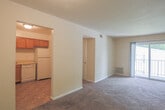 Located at 168 Heritage Way in Newport News, Virginia, this single-floor residence offers a practical and comfortable layout designed for everyday living. The living room is spacious and carpeted, featuring neutral beige walls and a sliding glass door that opens onto a private balcony with outdoor views of surrounding greenery, allowing natural light to fill the space. A wall-mounted HVAC unit provides climate control convenience. The kitchen is well-appointed with warm oak cabinetry extending to the ceiling for ample storage, light-colored countertops, tile flooring, and white appliances including a refrigerator, dishwasher, and electric range. The space includes multiple bedrooms, each finished with plush carpeting, neutral walls, and natural light from windows. Several bedrooms feature built-in closets with overhead storage, providing generous organizational space. One bedroom includes a private en-suite bathroom. The bathrooms are finished in white, with one featuring a full tub-shower combination with a paneled surround and chrome fixtures, and another with classic white tile. The overall design is clean and functional, offering a straightforward, move-in-ready living environment in a residential Newport News neighborhood.