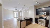 Located at 808 Hawthorne Ln in Charlotte's vibrant 28204 zip code, this one-bedroom, one-bathroom unit offers a well-designed single-floor layout with a comfortable and functional use of space. Light-toned hardwood flooring flows consistently throughout, creating a bright and cohesive aesthetic across all rooms.

The open-concept kitchen and living area serves as the heart of the home. The kitchen is appointed with rich dark cabinetry, a subway tile backsplash, stainless steel appliances including a refrigerator, range, and microwave, and a peninsula island topped with dark granite countertops. Pendant lighting and a track light fixture illuminate the space stylishly. The living area is spacious and airy, featuring a ceiling fan and French doors that lead to an outdoor area, welcoming abundant natural light.

The generously sized primary bedroom includes a ceiling fan, soft neutral walls, and direct access to a dedicated closet with built-in hanging storage. The bathroom offers a clean, modern design with dark-framed cabinetry, a white quartz countertop, an undermount sink, and a large framed mirror with overhead vanity lighting. Tile flooring completes the bathroom's polished look. The unit's neutral palette and modern finishes create a refined, move-in-ready atmosphere throughout.