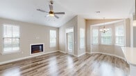 Located at Arbor Landing in Biloxi, Mississippi, this single-story residence offers a well-designed open layout with a clean, modern aesthetic defined by neutral tones and quality finishes throughout. The main living area makes an immediate impression with its vaulted ceilings and a ceiling fan overhead, creating a sense of openness and airflow. Large windows allow abundant natural light to fill the space, while a built-in fireplace serves as a focal point along one wall. A glass-paned door provides access to an outdoor area, further enhancing the connection to the surroundings.

The kitchen is thoughtfully appointed with crisp white shaker-style cabinetry, light quartz countertops, and stainless steel appliances including a refrigerator, range, and built-in microwave. Wood-look hard flooring runs throughout the main living and kitchen areas, adding warmth and cohesion. A dedicated dining area nearby features a decorative chandelier.

The bedroom is carpeted and generously proportioned, with access to a closet and a hallway that leads to the bathroom. The bathroom is outfitted with a white vanity, quartz countertop, undermount sink, and a tub-shower combination with tiled surround. A dedicated laundry area with hookups completes this well-organized, move-in-ready residence.