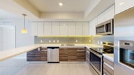 Located at The Underline in Miami's vibrant Brickell neighborhood, this 2-bedroom, 2-bathroom residence offers a thoughtfully designed single-floor layout with modern finishes throughout. The open-concept living and kitchen area serves as the heart of the home, where large floor-to-ceiling sliding glass doors flood the space with natural light and frame sweeping views of the Miami skyline. The kitchen is a standout, featuring glossy white upper cabinetry with under-cabinet LED lighting, wood-toned lower cabinets, a tile backsplash, stainless steel appliances including a dishwasher, range, and refrigerator, and a peninsula with a clean white countertop ideal for dining or entertaining. Light-toned large-format tile flooring runs consistently throughout the unit, enhancing the bright, airy ambiance. The primary bedroom offers a comfortable footprint with a dedicated closet, while the second bedroom also enjoys direct balcony access with panoramic city views. Each bedroom is served by its own bathroom: one features a glass-enclosed walk-in shower with large-format tile surround, while the other includes a full soaking tub with shower combination. Both bathrooms share a cohesive design with wood-accented vanities and neutral tile finishes. Two closets provide ample storage throughout the home.