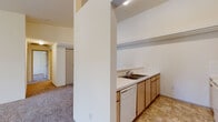 Located at 911 E Beacon Ave in Spokane, Washington, this 2-bedroom, 2-bathroom residence offers a practical and comfortable single-floor layout. The open-concept living area is highlighted by vaulted ceilings that lend an airy sense of space, with plush carpet flooring throughout and a sliding glass door that fills the room with natural light and provides access to an outdoor area.

The kitchen is efficiently designed with a galley-style layout, featuring light wood cabinetry, white tile backsplash, ample counter space, and white appliances including a stove, microwave, refrigerator, and dishwasher. A raised breakfast bar separates the kitchen from the living area, creating a convenient space for casual dining or entertaining.

Both bedrooms are carpeted and well-sized, with the primary bedroom offering a comfortable footprint suited for a full furniture arrangement. Each bedroom includes closet storage and easy access to the hallway connecting the rest of the unit.

The two bathrooms are clean and functional, each featuring a tub-shower combination, toilet, vanity with mirror, and tile flooring in a neutral diamond pattern. Light wood cabinetry in the bathrooms complements the overall design palette of the home. The hallway ties all rooms together in a straightforward, easy-to-navigate layout.