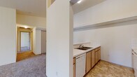 Located at 911 E Beacon Ave in Spokane, Washington, this 2-bedroom, 2-bathroom residence offers a practical and comfortable single-floor layout. The open-concept living area is highlighted by vaulted ceilings that lend an airy sense of space, with plush carpet flooring throughout and a sliding glass door that fills the room with natural light and provides access to an outdoor area.

The kitchen is efficiently designed with a galley-style layout, featuring light wood cabinetry, white tile backsplash, ample counter space, and white appliances including a stove, microwave, refrigerator, and dishwasher. A raised breakfast bar separates the kitchen from the living area, creating a convenient space for casual dining or entertaining.

Both bedrooms are carpeted and well-sized, with the primary bedroom offering a comfortable footprint suited for a full furniture arrangement. Each bedroom includes closet storage and easy access to the hallway connecting the rest of the unit.

The two bathrooms are clean and functional, each featuring a tub-shower combination, toilet, vanity with mirror, and tile flooring in a neutral diamond pattern. Light wood cabinetry in the bathrooms complements the overall design palette of the home. The hallway ties all rooms together in a straightforward, easy-to-navigate layout.