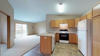 Located at 924 Songbird Ln in Stevens Point, Wisconsin, this single-floor unit offers a practical and comfortable layout designed for everyday living. The open-concept kitchen flows seamlessly into the living area, creating a connected and sociable space. The kitchen is equipped with warm honey-toned oak cabinetry offering generous storage, a peninsula with an integrated sink, a dishwasher, electric range, and a full-size refrigerator. Durable stone-look tile flooring grounds the kitchen and extends into the dining and entry areas, where a classic chandelier adds a decorative touch above the dining space. The living area transitions to soft carpeting and is brightened by a sliding glass door that opens to a private balcony. Bedrooms are carpeted and well-sized, each featuring closets with full-length hanging rods for ample storage. The bathroom is finished with stone-look tile flooring, a wide vanity with a generous countertop and large mirror, and a tub-shower combination. A dedicated in-unit laundry closet accommodates a full-size washer and dryer side by side. Additional storage is provided throughout, including a coat closet near the entry. The overall palette of neutral tones and warm wood accents creates a clean, welcoming ambiance throughout the home.