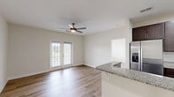 Located at 1010 Flats Ave in Mebane, NC, this well-appointed two-bedroom, two-bathroom home offers comfortable single-floor living with a thoughtful layout and modern finishes throughout. The open-concept living and dining area is anchored by wood-style plank flooring, neutral walls, and a ceiling fan, while French doors flood the space with natural light and provide outdoor access. The kitchen is a standout feature, boasting rich dark-espresso cabinetry, granite countertops with a tile backsplash, stainless steel appliances including a refrigerator and dishwasher, and a peninsula with a double-basin sink — ideal for both cooking and entertaining. The generously sized primary bedroom features hardwood-style flooring and a ceiling fan, while the second bedroom is finished with plush carpeting for added comfort. Each bedroom is served by its own closet, including a walk-in closet with wire shelving for organized storage. Both bathrooms are clean and functional, with one featuring a full tub-shower combo with built-in shelving. A dedicated laundry room with washer and dryer hookups adds everyday convenience. The home's consistent use of neutral tones and quality materials creates a bright, cohesive, and move-in-ready living environment.