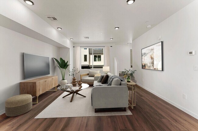 Elegante sala de estar con decoración moderna, grandes ventanales que aportan luz natural, cómodos asientos y elegantes suelos de madera. - Coal Creek Townhomes