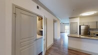 This single-story residence offers a thoughtfully designed layout that balances functional living spaces with modern finishes throughout. The kitchen serves as a central highlight, featuring granite countertops, a subway tile backsplash, gray cabinetry, and a full suite of stainless steel appliances including a range, over-the-range microwave, and dishwasher. A peninsula with an integrated sink adds additional prep space and promotes an open connection to the adjoining areas.

Wood-style plank flooring runs through the main living and kitchen areas, complemented by crown molding details that lend a polished character to the space. The living area is bright and open, with a sliding glass door fitted with vertical blinds that leads to a private balcony overlooking greenery. Ceiling fans are present in multiple rooms, including the bedrooms, which feature plush carpeting for added comfort.

A dedicated laundry closet with washer and dryer connections provides in-unit convenience. The bathroom includes a vanity with a white countertop, gray cabinetry, a wall-mounted medicine cabinet, and a tiled tub-shower combination. The overall palette of neutral tones and clean finishes creates a cohesive, contemporary ambiance throughout the home.