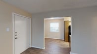 This single-story unit at 1380 E Seminary Dr in Fort Worth, Texas, offers a practical and straightforward layout designed for comfortable everyday living. The entryway welcomes residents through a solid front door into a foyer that transitions between wood-look flooring and carpeted areas, establishing a clear division between living and sleeping spaces.

The living area connects openly to a dining space, with a window providing natural light and views of the surrounding neighborhood. Wood-look plank flooring runs throughout the main living zones, adding warmth and durability underfoot. A hallway with the same flooring links the various rooms and features textured walls consistent with the unit's overall aesthetic.

The galley-style kitchen is efficiently arranged, featuring dark cabinetry, a black refrigerator and range, a stainless steel sink, and ample upper and lower cabinet storage. A textured ceiling continues throughout this area.

The bedrooms are carpeted and well-proportioned, each featuring a window with blinds that allow for natural light and outdoor views. Ceiling fans are present, enhancing comfort. A notable walk-in closet provides generous storage within the sleeping quarters.

The bathroom is well-appointed with wood-look tile flooring, large-format wall tiles surrounding the tub-shower combination, a vanity with a mirror, and a window for ventilation and natural light. Textured ceilings are consistent throughout the unit.