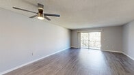 Located at 5528 Cinderlane Pkwy in Orlando, FL, this well-appointed 1-bedroom, 2-bathroom residence offers a thoughtfully designed single-floor layout. The expansive living area is the heart of the home, featuring rich hardwood-style flooring, neutral gray walls, a textured ceiling, and a modern ceiling fan with integrated lighting. Sliding glass doors flood the space with natural light and open directly onto a private balcony overlooking lush greenery, creating a seamless indoor-outdoor connection. Multiple living areas provide flexible space for lounging, dining, or working from home. The bedroom is generously sized, accommodating a variety of furniture arrangements, and includes a walk-in closet with built-in shelving for ample storage. The en-suite primary bathroom is a standout feature, boasting a long dual-sink vanity with stone-look countertops, white cabinetry, large mirrors with overhead lighting, and a separate tiled tub-shower combination. A second full bathroom mirrors this quality. Additional highlights include a dedicated laundry area, multiple closets throughout, and hardwood-style flooring carried consistently across the home. The clean, neutral palette and well-maintained finishes create a bright, move-in-ready atmosphere throughout.