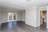 Located at 55 Pharr Rd NW in Atlanta's prestigious Buckhead neighborhood, this single-floor unit offers a well-appointed layout with a cohesive design throughout. The living area features rich, dark hardwood-style flooring and crown molding that frame the space with a polished finish. A textured ceiling adds depth, while French doors at the rear of the living room invite natural light and provide direct access to the outdoors.

The kitchen is thoughtfully updated with white shaker-style cabinetry, granite countertops, a subway tile backsplash, and stainless steel appliances including a refrigerator, range, and dishwasher. A deep single-basin sink with a flexible pull-down faucet completes the functional workspace, all set atop matching hardwood-style flooring.

The bedroom offers plush carpeting, crown molding, a ceiling fan with integrated lighting, and a window with blinds that allows for natural light and ventilation. The hallway connects to a dedicated bathroom featuring tile flooring and a wall-mounted light fixture, keeping utilities neatly organized and accessible.

Throughout the unit, neutral warm-gray walls provide a versatile backdrop, while white trim and consistent finishes tie each room together into a cohesive and practical living space.