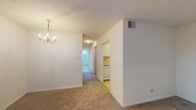 Located at 1809 Fairfax Rd in Greensboro, NC, this single-floor unit offers a straightforward, functional layout designed for comfortable everyday living. The main living and dining area is generously proportioned, finished with neutral-toned carpet and accented by an elegant chandelier that adds a touch of warmth to the space. A large sliding glass door fitted with vertical blinds allows an abundance of natural light to fill the room while providing access to the outdoors.

A central hallway connects the living areas to the private rooms, creating a logical and efficient flow throughout the unit. The galley-style kitchen features white cabinetry with ample storage, light countertops, a stainless steel sink, an electric range, and a full-size refrigerator, all set atop easy-to-maintain tile flooring.

The bedrooms are carpeted and finished with neutral walls, each benefiting from windows dressed with blinds that invite natural light and offer views of the surrounding greenery. The rooms provide versatile, open spaces suitable for a variety of configurations.

The bathroom is well-appointed with a double-sink vanity topped by a wide mirror and a lighted fixture, a tub-shower combination, and tile flooring, delivering both practicality and functionality. Overall, the unit presents a clean, understated aesthetic throughout.