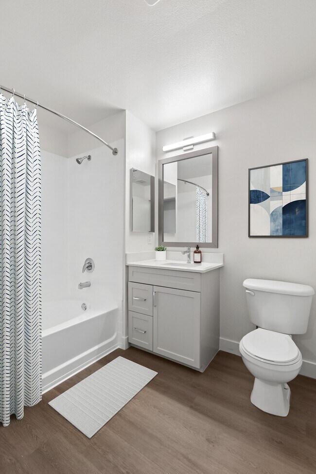 Baño renovado del paquete II con gabinetes grises, encimeras de cuarzo blanco y pisos de superficie dura. - Avalon at Cahill Park