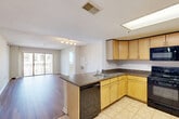 Located at 1215 East West Highway in Silver Spring, MD, this two-bedroom, two-bathroom residence offers a well-designed single-level layout with a comfortable and functional flow throughout. The open-concept kitchen and living area serves as the heart of the home, where light maple cabinetry, dark granite countertops, a peninsula with a built-in sink, and black appliances — including a gas range, dishwasher, microwave, and refrigerator — define a fully equipped kitchen. A skylight-style overhead fixture adds brightness to the kitchen space. The living area extends naturally from the kitchen, featuring hardwood-style flooring and a sliding glass door that opens to a private balcony with outdoor views. The spacious primary bedroom features plush carpeting and ample closet space, while the second bedroom also offers carpet flooring and a large window that fills the room with natural light. Six closets are distributed throughout, providing generous storage. Both bathrooms are finished with white tile flooring; one includes a full tub-shower combination, wood-toned vanity, and a wide mirror. The entrance leads conveniently into the main living spaces, and the overall neutral color palette creates a bright, clean ambiance throughout the home.