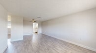 Located in South Daytona, Florida, this single-story 2-bedroom, 1-bathroom home offers a clean, functional layout with thoughtful finishes throughout. The combined living and dining area is a bright, open space featuring light gray luxury vinyl plank flooring, a textured ceiling, a ceiling fan, and neutral walls that maximize natural light. A front-facing window and entry door add to the airy feel of this central gathering space. The kitchen is well-appointed with white cabinetry, stone-look countertops, a white subway tile backsplash, a stainless steel double-basin sink, and a window that brings in natural light. Both bedrooms are carpeted in warm beige tones and include windows with blinds providing outdoor views. The primary bedroom offers a built-in closet with sliding panel doors, while additional closets throughout the home provide ample storage. The bathroom features wood-look tile flooring, a tub-shower combination with white tile surround, a single-sink vanity, and a medicine cabinet with shelving. A dedicated utility room rounds out the practical floor plan. The home's consistent use of light, neutral tones and updated finishes creates a clean, move-in-ready atmosphere throughout.