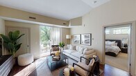 This 1-bedroom, 1-bathroom residence is designed with a smart, functional layout that makes excellent use of its space. The living area is bright and welcoming, featuring rich hardwood flooring, warm neutral walls, and vaulted ceiling details that lend a sense of openness. Large sliding glass doors flood the room with natural light and open directly onto a private balcony overlooking lush, mature tree canopy — a standout feature that brings the outdoors in.

The kitchen is a highlight of the home, showcasing dark espresso cabinetry extending to the ceiling, granite countertops, stainless steel appliances including a refrigerator, range, and microwave, and a peninsula with bar seating — ideal for casual dining or entertaining.

The bedroom is a calm retreat, carpeted for comfort, with windows that frame peaceful greenery. It offers generous space for furnishings and is positioned adjacent to the full bathroom.

The bathroom is finished with a dark-toned vanity, granite countertop, a framed mirror, and a glass-enclosed walk-in shower with tile surround and built-in niches, completing the cohesive, modern aesthetic found throughout the residence.