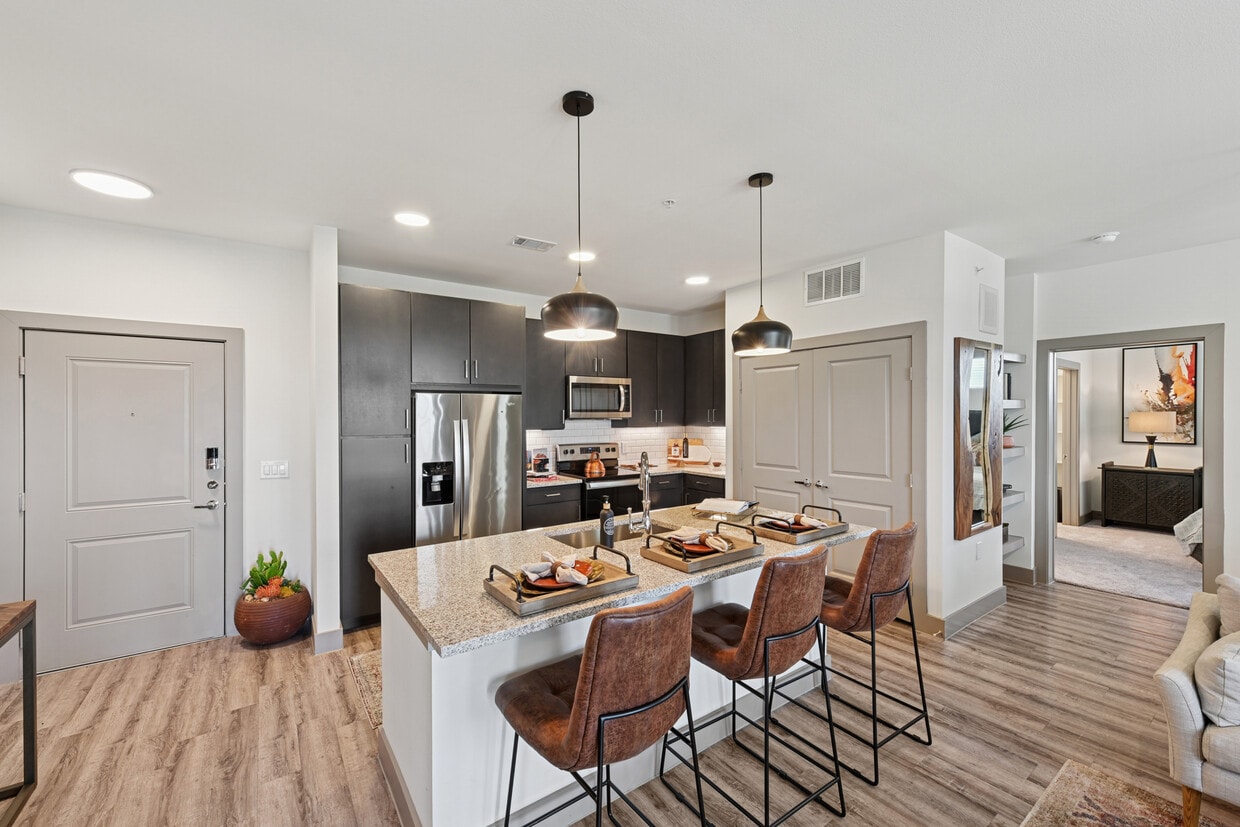 Kitchen with espresso cabinetry, speckled granite countertops, white subway tile backsplash, stainless steel appliances, and hard surface flooring - Avalon Benbrook