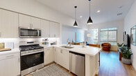 Located at 1800 Santa Carolina Rd in Chula Vista, CA, this thoughtfully designed one-bedroom, one-bathroom residence offers a cohesive open-concept layout that seamlessly connects the kitchen, dining, and living areas. The modern kitchen is a functional centerpiece, featuring white shaker-style cabinetry extending to tall ceilings, stainless steel appliances including a gas range, microwave, dishwasher, and refrigerator, a white quartz peninsula with bar seating, and stylish pendant lighting overhead. Light wood-style flooring flows throughout the main living areas, enhancing the bright, airy ambiance. The living room is generously proportioned with tall ceilings and a sliding glass door that opens to a private balcony, allowing natural light to fill the space. The spacious primary bedroom features plush carpet, a ceiling fan, a large window with outdoor views, and ample room for a full furniture arrangement. The bathroom is finished with a white quartz vanity, modern cabinetry, and a large mirror. Clean neutral walls and recessed lighting throughout create a consistent, contemporary aesthetic well-suited for comfortable everyday living.