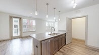 Located at 12300 Moores Lake Rd in Chester, VA, this 3-bedroom, 2-bathroom unit offers a thoughtfully designed single-floor layout with contemporary finishes throughout. The open-concept living room and kitchen area is anchored by warm wood-look plank flooring, large windows with blinds that flood the space with natural light, and a ceiling fan for added comfort. The kitchen is well-appointed with granite countertops, a spacious peninsula with an undermount sink, taupe shaker-style cabinetry, stainless steel appliances including a refrigerator, range, and microwave, plus track and pendant lighting overhead. Both bathrooms continue the granite countertop theme, featuring wood-toned vanities and wood-look flooring. One bathroom includes a tub/shower combo with a curved rod, while the other offers a wide vanity with a large mirror and bright vanity lighting. The three bedrooms are carpeted for comfort; the generously sized primary bedroom features a wall of windows with treetop views and a ceiling fan, while the additional bedrooms include closets and ceiling fans. A dedicated laundry room houses a full-size washer. Two closets provide ample storage throughout the unit.