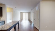 This single-floor, 3-bedroom, 2-bathroom residence offers a thoughtfully designed layout that maximizes functionality and comfort. The open-concept kitchen and living area serves as the heart of the home, featuring rich dark wood cabinetry, granite countertops, stainless steel appliances including a refrigerator, range, microwave, and dishwasher, and a central island with additional storage. Gleaming hardwood-style flooring flows throughout the main living areas, complemented by neutral-toned walls that create a clean, modern aesthetic. The living room receives natural light through a large sliding glass door dressed with vertical blinds, lending an airy, open feel to the space. The bedrooms are carpeted for added comfort, with the primary bedroom offering generous proportions and a walk-in closet outfitted with wire shelving and hanging rods for ample storage. Both bathrooms are finished with tile surround tub-shower combinations, brushed nickel fixtures, and clean white cabinetry with solid countertops. The overall design is contemporary and cohesive, with practical finishes throughout that balance style and everyday livability.