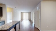 This single-floor, 3-bedroom, 2-bathroom residence offers a thoughtfully designed layout that maximizes functionality and comfort. The open-concept kitchen and living area serves as the heart of the home, featuring rich dark wood cabinetry, granite countertops, stainless steel appliances including a refrigerator, range, microwave, and dishwasher, and a central island with additional storage. Gleaming hardwood-style flooring flows throughout the main living areas, complemented by neutral-toned walls that create a clean, modern aesthetic. The living room receives natural light through a large sliding glass door dressed with vertical blinds, lending an airy, open feel to the space. The bedrooms are carpeted for added comfort, with the primary bedroom offering generous proportions and a walk-in closet outfitted with wire shelving and hanging rods for ample storage. Both bathrooms are finished with tile surround tub-shower combinations, brushed nickel fixtures, and clean white cabinetry with solid countertops. The overall design is contemporary and cohesive, with practical finishes throughout that balance style and everyday livability.