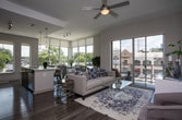 This single-floor residence showcases a thoughtfully designed open-concept layout with contemporary finishes throughout. The kitchen is a functional centerpiece, outfitted with dark flat-front cabinetry, white quartz countertops, a classic subway tile backsplash, and a full suite of stainless steel appliances including a gas range, over-the-range microwave, and French door refrigerator. A large island provides additional prep and seating space, flowing naturally into the dining and living areas.

The dining area is distinguished by floor-to-ceiling windows that flood the space with natural light and offer expansive urban views, creating an airy, connected atmosphere. The living room continues this theme with a sliding glass door that opens to the outdoors, further enhancing the sense of openness.

The primary bedroom features plush carpeting, soft neutral tones, and direct access to an en-suite bathroom complete with large-format tile flooring, a tiled walk-in shower, a soaking tub, and a dark-wood double vanity with stone countertops. A walk-in closet is also accessible from the suite. Additional bedrooms are generously proportioned with carpeted floors, ample natural light, and urban views. Wood-look flooring runs throughout the main living areas, unifying the overall aesthetic.