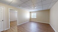 Located at 1225 E Cherry St in Springfield, MO, this thoughtfully designed one-bedroom, two-bathroom unit offers a comfortable and functional layout across a single floor. The kitchen is a standout feature, showcasing warm medium-toned wood cabinetry with ample upper and lower storage, light countertops, a stainless steel refrigerator, and a dishwasher — all set atop durable wood-look flooring that flows consistently throughout the space. The L-shaped kitchen layout maximizes efficiency and workspace. The spacious primary bedroom receives natural light through a window fitted with blinds and features the same wood-look flooring, neutral warm-toned walls, and a drop tile ceiling. A dedicated closet provides generous storage. The hallway connects the bedroom to both bathrooms, one of which includes a full soaking tub surrounded by classic white subway tile and brushed gold fixtures — a clean, timeless design. The second bathroom features dark vanity cabinetry. Neutral beige tones on the walls and white trim throughout lend a cohesive, welcoming ambiance to the entire unit. Drop tile ceilings are consistent across all rooms, contributing to a uniform and polished finish.