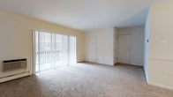 Located at 1901 W Chester Pike in Havertown, Pennsylvania, this single-floor residence offers a clean, well-maintained living environment with a straightforward and functional layout. The living area is a standout feature, characterized by its open feel, neutral wall tones, and plush wall-to-wall carpeting that adds warmth underfoot. A full-width sliding glass door fitted with vertical blinds allows an abundance of natural light to fill the space while offering direct access to an outdoor area and views of the surrounding greenery. Two interior doors are visible within the main living space, providing convenient access to additional rooms or storage areas, each with closet space to help maximize organization. The high, smooth white ceilings contribute to an airy and spacious atmosphere throughout. The overall palette of soft whites and warm beiges creates a neutral and versatile backdrop, making the space easy to personalize. Situated in Havertown, PA, the property benefits from a well-established suburban setting with convenient access to local amenities, dining, and major transit routes along West Chester Pike.