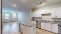 This one-bedroom, one-bathroom unit at Chatham Center Drive in Savannah, Georgia offers a well-designed, single-floor layout with a clean, contemporary aesthetic. The open-concept kitchen and living area form the heart of the space, where light wood-style flooring, neutral walls, and track lighting create a bright, cohesive environment. The kitchen is thoughtfully equipped with white shaker cabinetry, granite countertops, a suite of stainless steel appliances—including a refrigerator, range, microwave, and dishwasher—and a freestanding island with a matching granite surface, providing additional workspace and casual seating potential. The living area extends naturally from the kitchen, with a ceiling fan and a window that draws in natural light.

The bedroom features plush carpeting, a ceiling fan with light fixture, and a window with blinds, contributing to a comfortable and restful atmosphere. An adjacent walk-in closet offers wire shelving and hanging rods on multiple walls, providing practical and organized storage. The bathroom connects directly to the bedroom area and includes a granite-topped vanity with white cabinetry, a tub-shower combination, and the same light wood-style flooring found throughout the main living spaces. The overall design maintains a consistent modern palette, making this a functional and attractive single-level residence.