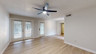 This well-appointed single-floor residence offers a thoughtfully designed layout comprising one bedroom, one bathroom, a living room, and a kitchen. Light hardwood flooring runs throughout the space, lending warmth and visual continuity to every room. The living area is open and airy, featuring a ceiling fan with built-in lighting and multiple windows with blinds that allow generous natural light to filter in. A glass-paned exterior door opens to the outside, enhancing the sense of openness. Track lighting in the hallway provides additional illumination leading to the private areas of the home. The kitchen is outfitted with clean white cabinetry, speckled quartz countertops, and a stainless steel undermount sink accented by a sleek matte black pull-down faucet. The generously sized bedroom accommodates a ceiling fan, two closet doors, and a window that brings in natural light. The bathroom is a standout, featuring marble-look tile on both the floors and full tub surround, a soaking bathtub with modern fixtures, and a contemporary white vanity. Neutral wall tones throughout create a clean, cohesive aesthetic, making this a practical and modern living space.