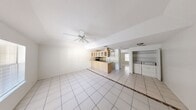 This single-story home offers a practical and efficient layout that maximizes every square foot of living space. Light-colored ceramic tile flooring runs consistently throughout the entire home, lending a clean and cohesive aesthetic to each room.

The open-concept living and dining area forms the heart of the home, featuring a ceiling fan overhead and a large window that invites natural light and offers outdoor views. This airy space flows seamlessly into the kitchen, which is anchored by a peninsula-style breakfast bar that doubles as a dining counter. The kitchen is well-appointed with light wood cabinetry featuring glass-front upper cabinets, ample counter space, a double sink, and a full suite of appliances including a black electric range, over-the-range microwave, refrigerator, and dishwasher.

Adjacent to the kitchen, a dedicated laundry area with built-in shelving provides convenient in-unit washer and dryer access. Two closets offer generous storage throughout the home.

The spacious bedroom is a comfortable retreat, featuring a ceiling fan, a large window with natural light, and tile flooring consistent with the rest of the home. The bathroom includes a vanity with wood cabinetry, a shower/tub combination, and tiled flooring, completing this practical and move-in-ready home.