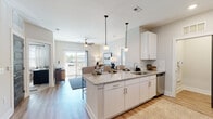 This well-appointed single-floor residence offers a thoughtfully designed open-concept layout that seamlessly connects the kitchen, dining, and living areas. The kitchen is a standout feature, showcasing crisp white cabinetry, granite countertops, a subway tile backsplash, and a full suite of stainless steel appliances including a refrigerator with ice maker, electric range, built-in microwave, and dishwasher. A peninsula with bar seating and pendant lighting serves as both a functional workspace and a casual dining spot, while recessed lighting illuminates the space throughout.

The living area flows naturally from the kitchen and opens to a private balcony through sliding glass doors, allowing natural light to fill the space. A ceiling fan adds comfort to this welcoming room.

The primary bedroom is a serene retreat with a natural light-filled window and an en-suite bathroom featuring a walk-in glass-enclosed shower and wood-look flooring. A secondary bedroom, equally bright with windows and a ceiling fan, offers flexible use as a guest room or home office. The second bathroom includes a full soaking tub and shower combination with tile surround and granite vanity. Wood-look flooring flows consistently throughout, tying the home's clean, contemporary aesthetic together.
