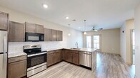 Located at 8660 N Wyandotte Street in Kansas City, MO, this one-bedroom, two-bathroom residence offers a thoughtfully designed single-floor layout. The entryway features light wood-look flooring and clean panel doors, setting a modern tone throughout the space. The kitchen is a standout feature, showcasing rich medium-toned cabinetry, light granite countertops, a white subway tile backsplash, and a full suite of stainless steel appliances including a refrigerator, range, microwave, and dishwasher. Pendant lighting over the peninsula and recessed ceiling lights add both style and functionality. The bedroom is comfortably sized with plush carpet flooring, a ceiling fan, a natural light-providing window with outdoor views, and a double sliding-door closet for ample storage. The primary bathroom is well-appointed with dark wood cabinetry, granite countertops, and large-format tile flooring. A separate tiled shower with glass sliding doors, a built-in bench seat, and a rainfall showerhead provides a spa-like experience. The second bathroom offers additional convenience. Throughout the residence, neutral tones and contemporary finishes create a cohesive, modern ambiance ideal for comfortable everyday living.