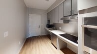 Located at 72 N Clinton Ave in the heart of downtown Rochester, New York, this single-floor unit offers a clean, modern design with consistent finishes throughout. Light-toned hardwood-style flooring runs continuously across the space, lending warmth and visual cohesion to every room.

The living area is bright and open, featuring neutral gray walls, recessed lighting, and a window with a roller shade that frames views of the Rochester skyline. Ample wall outlets and a straightforward layout make the space highly functional.

The kitchen is thoughtfully designed with gray flat-front cabinetry extending to the ceiling, providing generous storage. A stainless steel sink, electric cooktop, dishwasher, and microwave are included, along with a stainless steel backsplash and ventilation hood. The countertops are light-colored and continuous, offering practical workspace. A keyed entry door opens directly into the kitchen area.

The bedroom includes track lighting overhead, a large closet with paneled double doors, and a window overlooking the city, with a roller shade for privacy.

The bathroom is ADA-accessible, equipped with stainless steel grab bars positioned around the toilet and alongside a bathing area, all set against soft gray walls and matching flooring. The unit combines accessible functionality with a contemporary urban aesthetic.