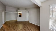 This single-floor residence offers a thoughtfully designed layout that balances open communal spaces with comfortable private areas. The living room welcomes you with warm hardwood-style flooring, neutral gray walls, and a textured ceiling, creating a bright and inviting atmosphere. A pass-through window connects the living area to the kitchen, enhancing the open feel of the space.

The kitchen is well-appointed with rich medium-toned wood cabinetry, dark granite countertops, and a full suite of black appliances including a range, microwave, refrigerator, and dishwasher. A built-in wine rack adds a distinctive touch above the pass-through, and ample cabinet storage ensures generous functionality.

The bedrooms feature plush carpeting, neutral tones, and textured ceilings. One bedroom includes mirrored sliding closet doors that reflect natural light from a nearby window, while another bedroom benefits from a bright window with exterior views. Both rooms offer comfortable proportions suited for a variety of furnishing arrangements.

The bathroom is finished with granite countertops, warm wood cabinetry, a full-width mirror, and a tiled shower, lending a clean and polished look. The entry foyer, also finished with hardwood-style flooring, provides a clear transition into the main living space. Overall, the residence presents a cohesive, practical design throughout.